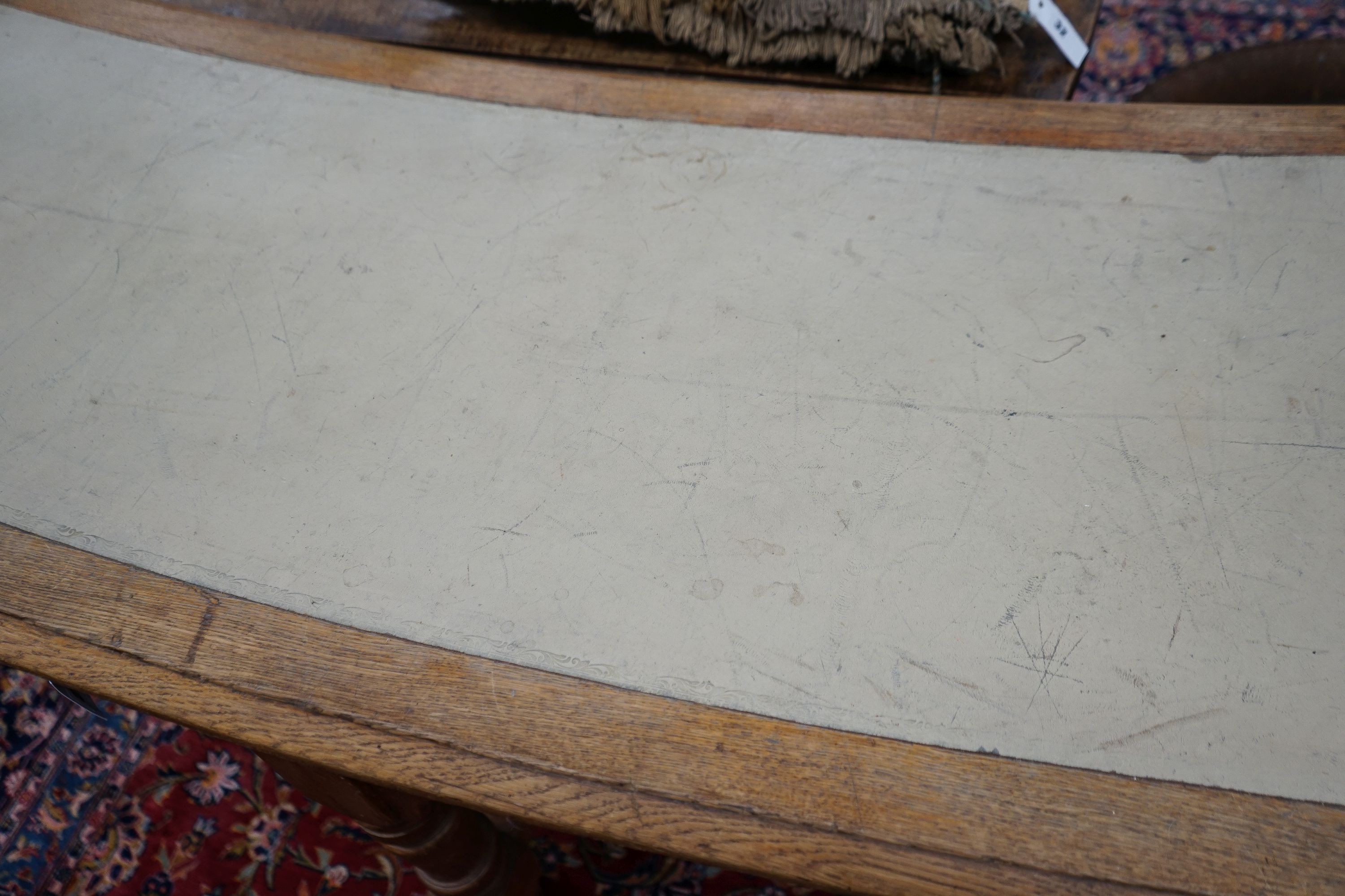 A late Victorian oak four drawer library table of curved rectangular form, length 240cm, depth 60cm, height 80cm